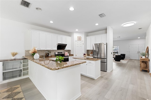 kitchen with kitchen peninsula, light wood-type flooring, light stone counters, stainless steel appliances, and white cabinets