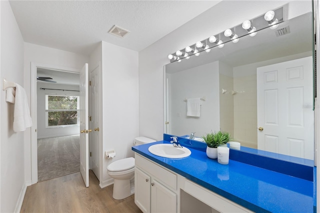 bathroom with toilet, vanity, a textured ceiling, and hardwood / wood-style flooring