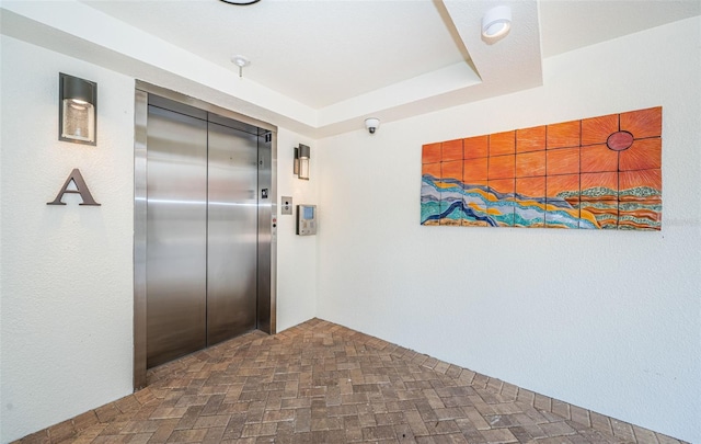 interior space with elevator and a raised ceiling