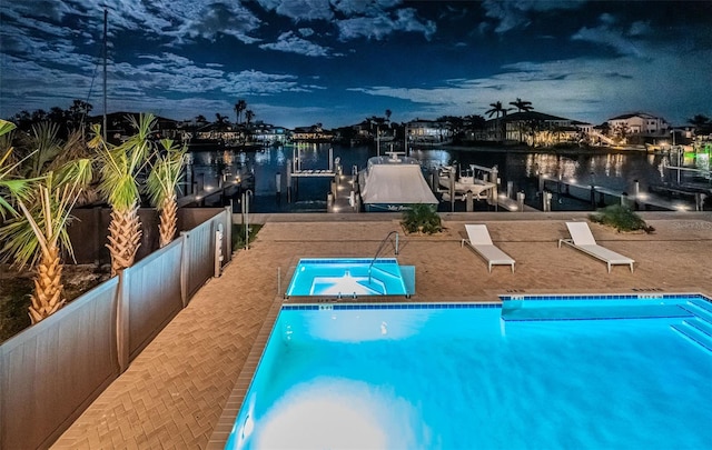 pool at dusk featuring a boat dock and a water view