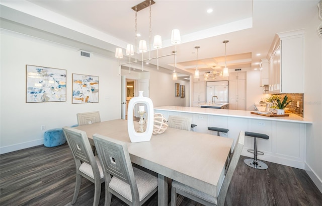 dining room featuring dark hardwood / wood-style flooring, a raised ceiling, and sink