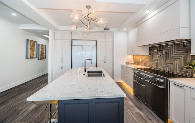 kitchen featuring a center island with sink, high quality appliances, white cabinetry, and backsplash