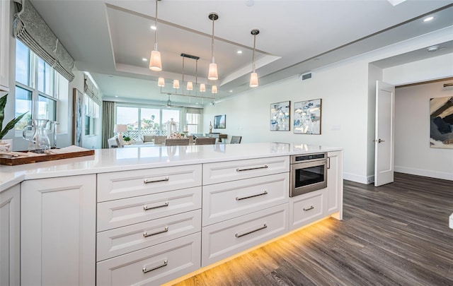 kitchen with white cabinets, pendant lighting, a tray ceiling, and dark hardwood / wood-style floors