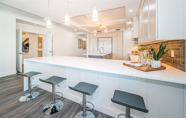 kitchen with pendant lighting, dark hardwood / wood-style flooring, white cabinets, and decorative backsplash