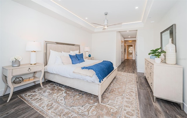 bedroom featuring dark hardwood / wood-style floors, ceiling fan, and a raised ceiling