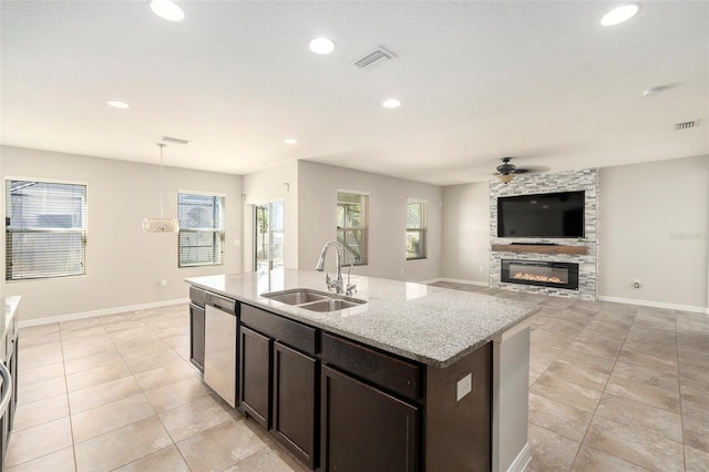 kitchen with stainless steel dishwasher, plenty of natural light, light stone counters, and sink