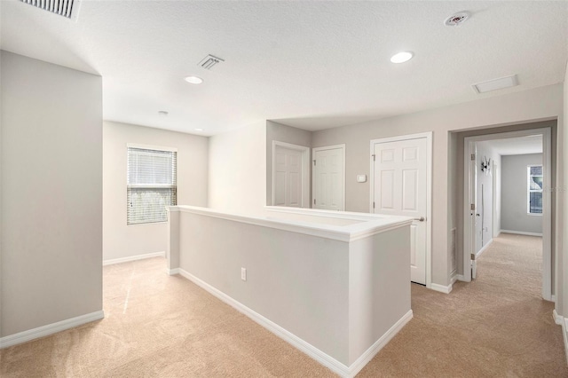 hall featuring a textured ceiling and light carpet