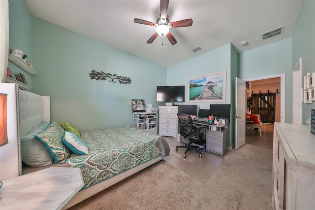 carpeted bedroom with ceiling fan and a barn door