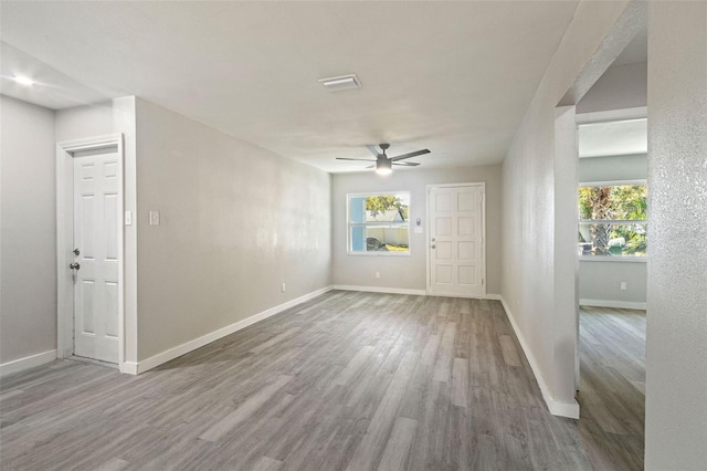 unfurnished room with a healthy amount of sunlight, wood finished floors, baseboards, and ceiling fan