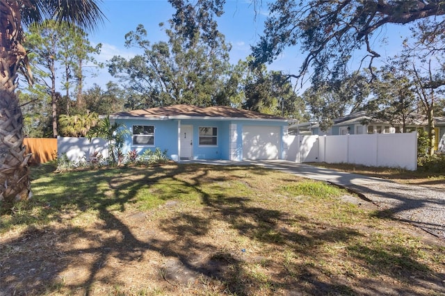 rear view of house with an attached garage, fence, driveway, and stucco siding