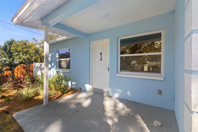 property entrance featuring fence, a patio, and stucco siding