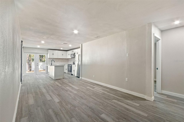 unfurnished living room with recessed lighting, french doors, baseboards, and wood finished floors