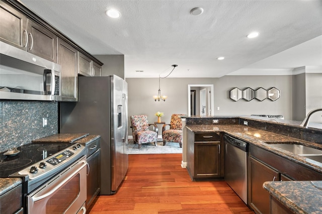 kitchen with sink, hanging light fixtures, decorative backsplash, dark brown cabinets, and appliances with stainless steel finishes