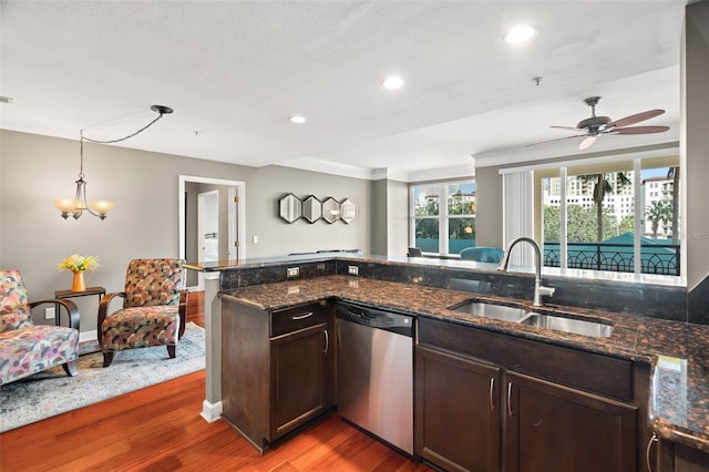 kitchen with stainless steel dishwasher, dark stone counters, ceiling fan with notable chandelier, sink, and dark hardwood / wood-style floors