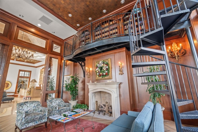 living room featuring wood walls, a high ceiling, ornamental molding, a notable chandelier, and wood ceiling