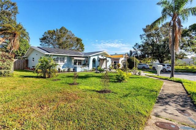 ranch-style house featuring solar panels and a front lawn