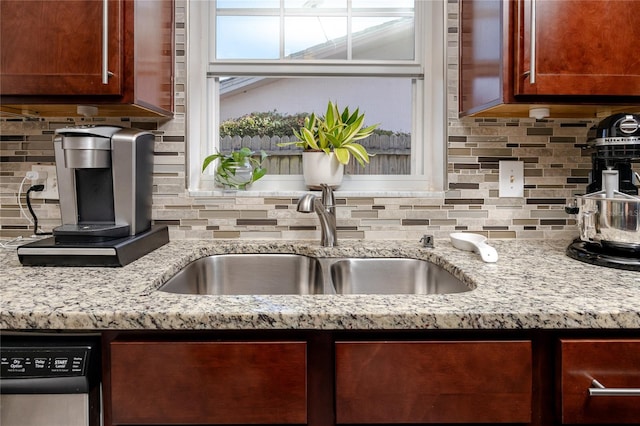 kitchen with stainless steel dishwasher, light stone counters, sink, and tasteful backsplash