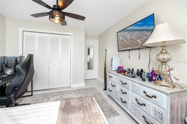 tiled office space featuring a textured ceiling and ceiling fan