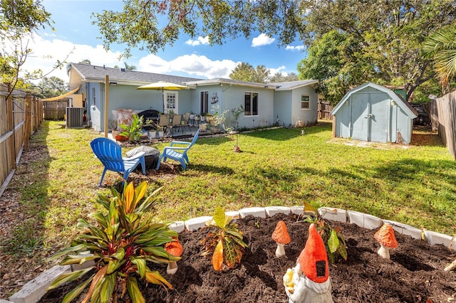 back of property with central AC unit, a storage unit, and a yard