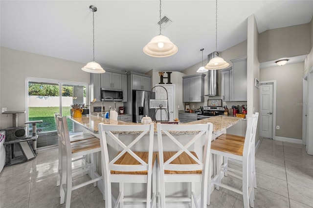 kitchen featuring gray cabinetry, pendant lighting, a breakfast bar area, and appliances with stainless steel finishes