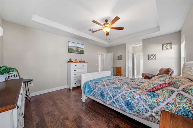 bedroom featuring ceiling fan, dark hardwood / wood-style floors, a closet, and a tray ceiling