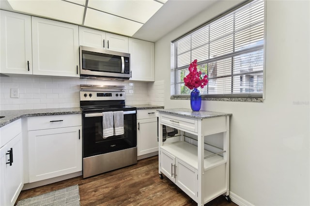 kitchen with white cabinets, appliances with stainless steel finishes, dark hardwood / wood-style floors, and dark stone countertops