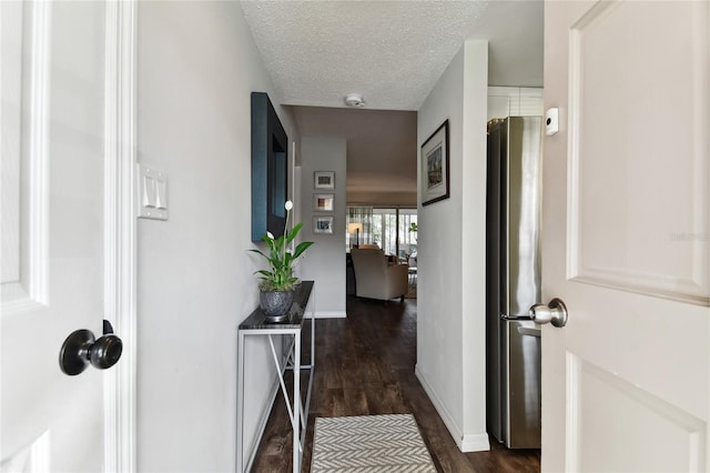 corridor with a textured ceiling and dark hardwood / wood-style floors