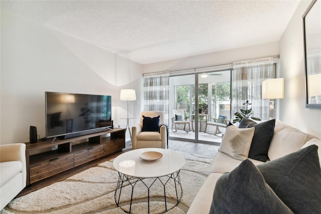 living room featuring ceiling fan, wood-type flooring, and a textured ceiling