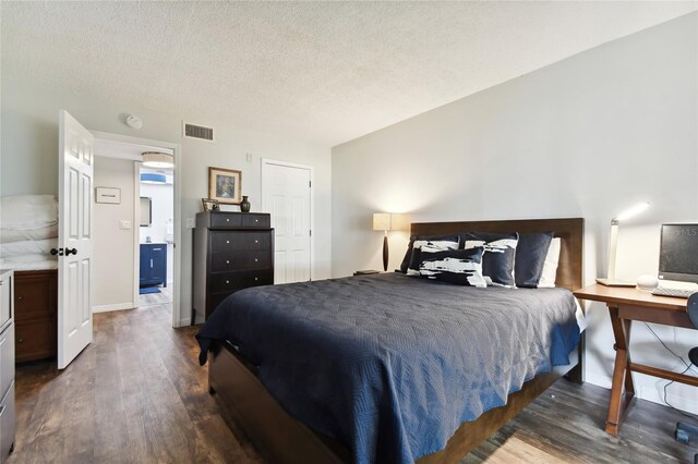 bedroom with a textured ceiling and dark hardwood / wood-style flooring