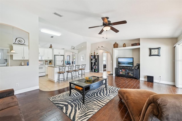 living room with ceiling fan, light hardwood / wood-style flooring, and vaulted ceiling