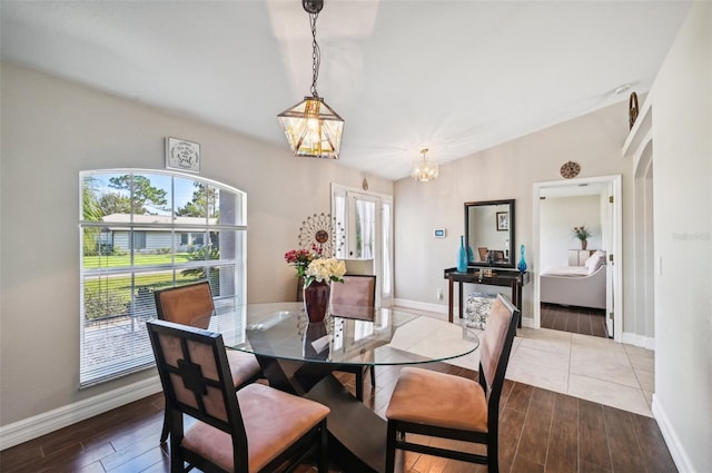 dining area featuring hardwood / wood-style floors, a notable chandelier, and vaulted ceiling