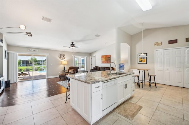 kitchen featuring white cabinets, sink, dishwasher, lofted ceiling, and an island with sink