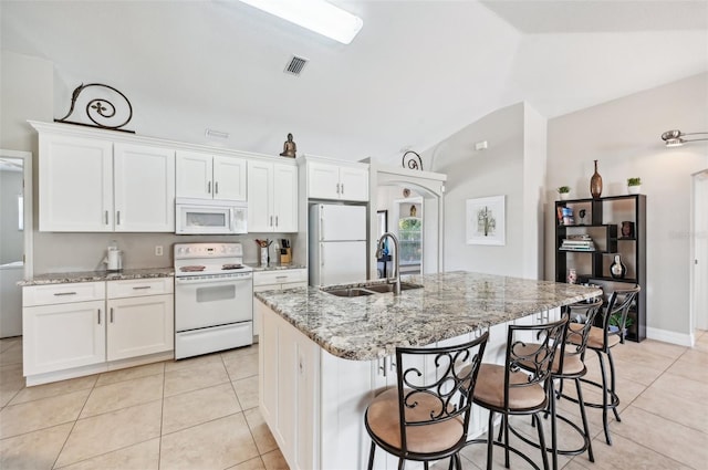 kitchen with white cabinets, lofted ceiling, an island with sink, and white appliances