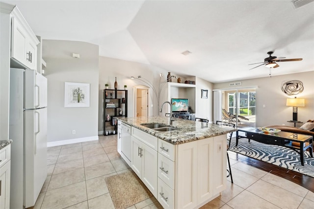 kitchen featuring sink, light stone counters, white appliances, a center island with sink, and white cabinets