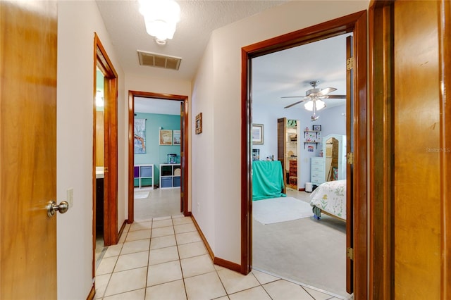 hall with light colored carpet and a textured ceiling