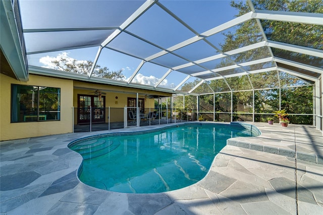 view of swimming pool with ceiling fan, a patio area, and glass enclosure