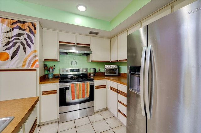 kitchen featuring light tile patterned floors, under cabinet range hood, stainless steel appliances, visible vents, and white cabinets