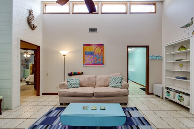 living area with baseboards, visible vents, a high ceiling, and light tile patterned flooring