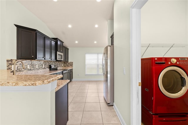 kitchen featuring sink, stainless steel appliances, washer / dryer, decorative backsplash, and light tile patterned floors