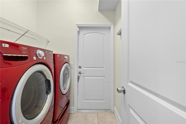 clothes washing area with washing machine and dryer and light tile patterned floors