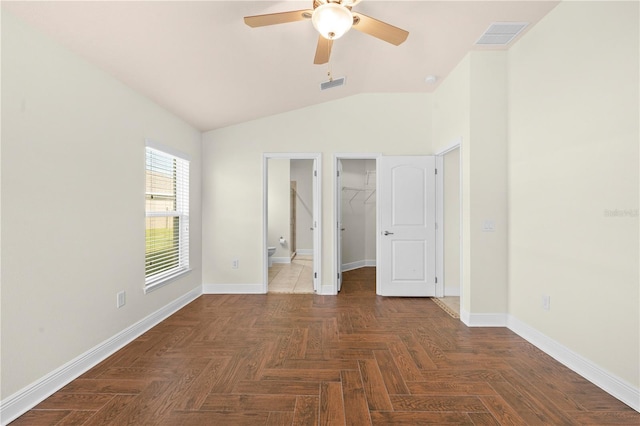 unfurnished bedroom featuring dark parquet flooring, vaulted ceiling, ceiling fan, a spacious closet, and connected bathroom