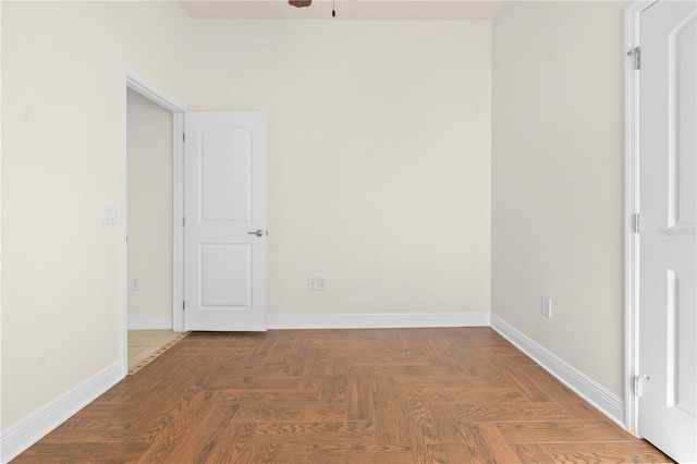 unfurnished room with dark parquet flooring and ceiling fan