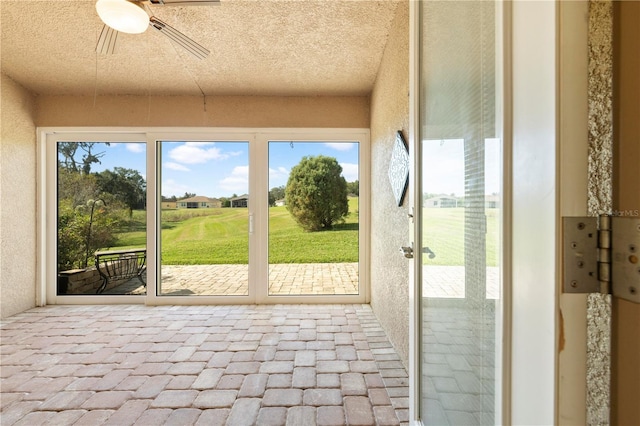 unfurnished sunroom featuring ceiling fan