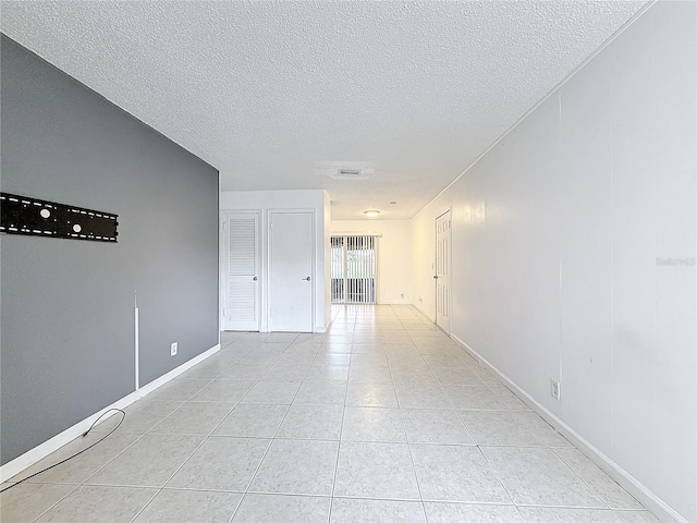 hallway featuring light tile patterned floors and a textured ceiling