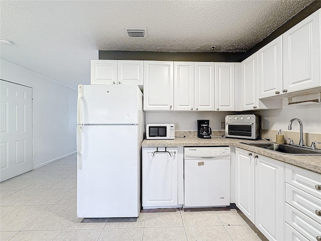 kitchen featuring white cabinetry, sink, a textured ceiling, white appliances, and light tile patterned floors