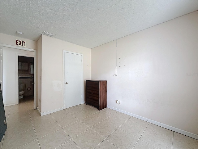 tiled empty room featuring a textured ceiling