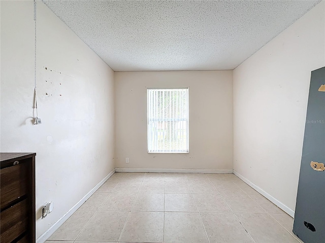 tiled empty room with a textured ceiling