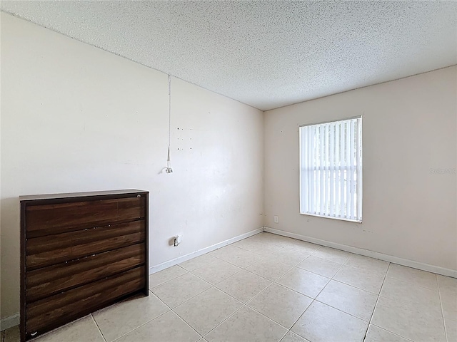 tiled empty room featuring a textured ceiling