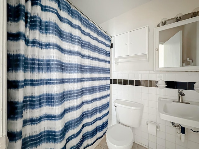 bathroom with tile patterned flooring, toilet, tile walls, and walk in shower