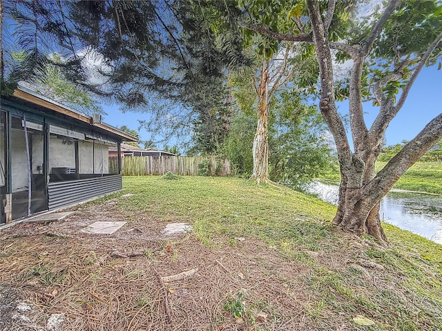 view of yard featuring a sunroom and a water view